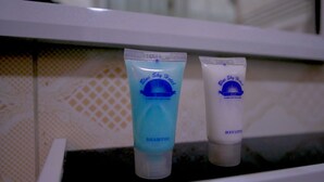 Two toiletry bottles labeled 'Blue Sky Hotel' on a white shelf.