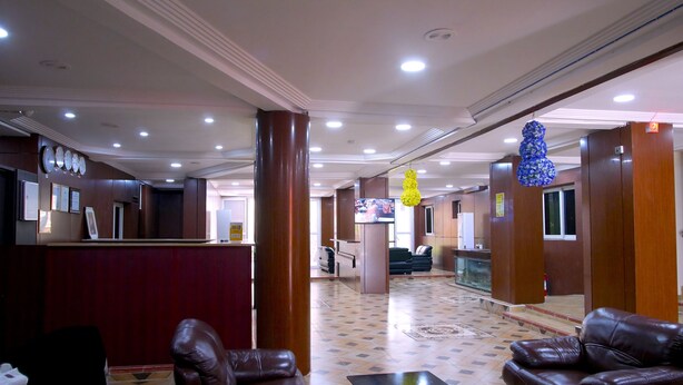 A hotel lobby with a reception desk, leather seating, a fish tank, and a television.