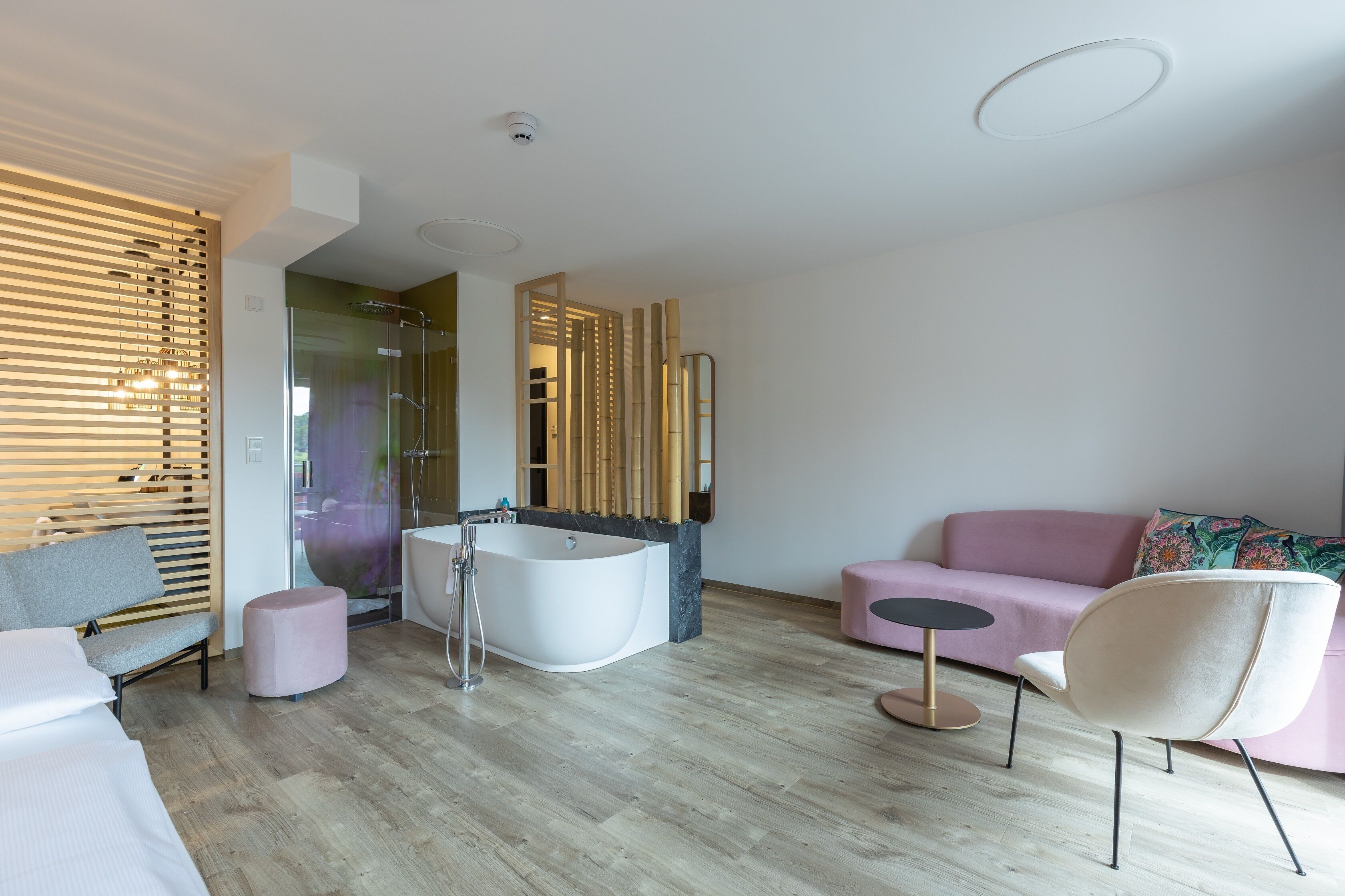 A modern bathroom with a freestanding bathtub, a glass shower enclosure, and a wooden privacy screen.