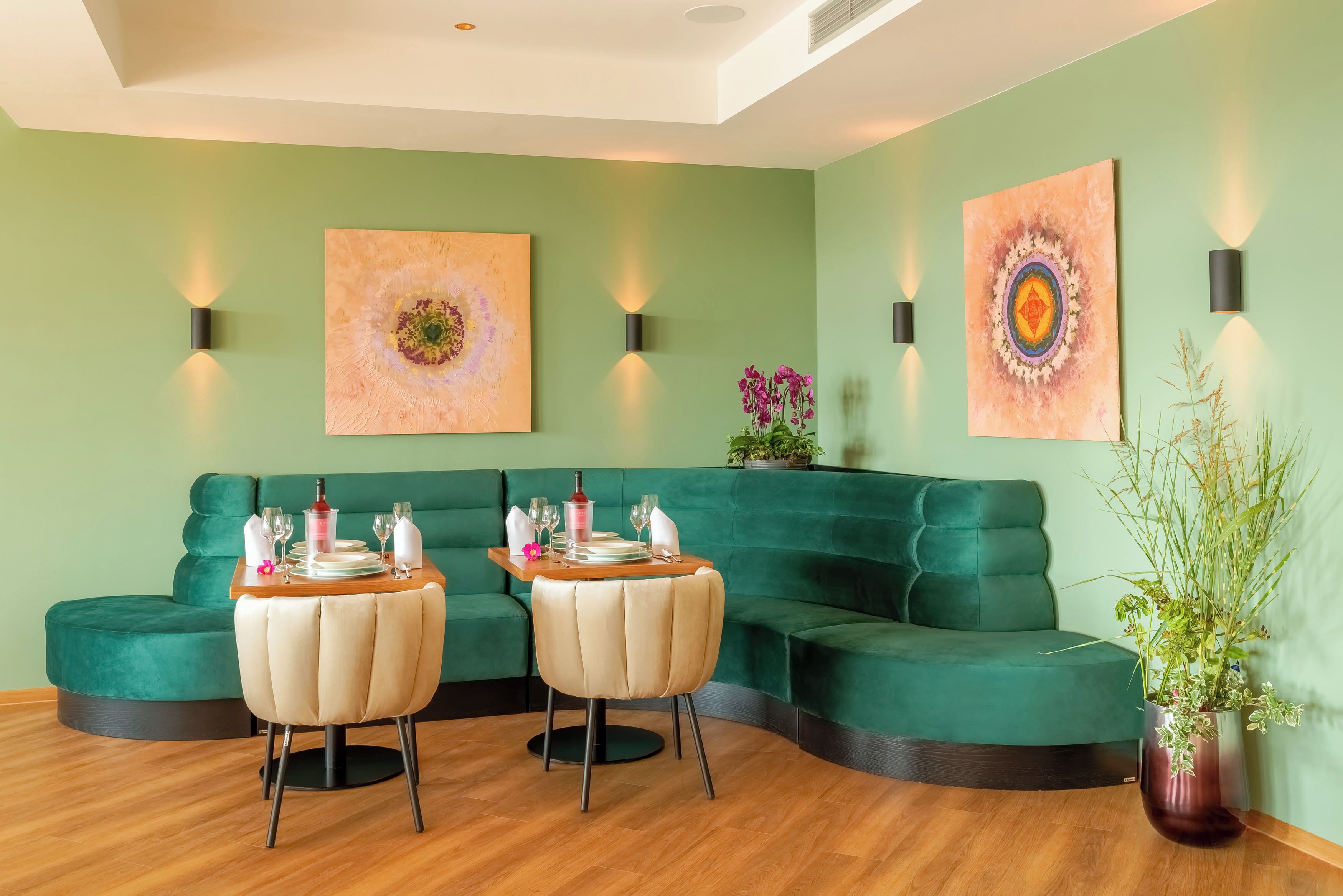 A modern living room with a green sofa, two armchairs, a wooden coffee table, and a vase with flowers.