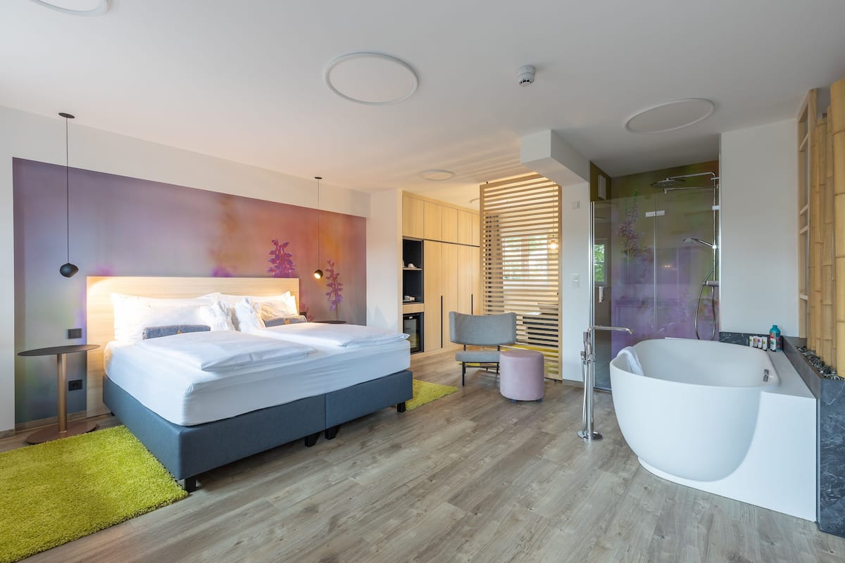 A modern bedroom with a large bed, a shower area, and a vanity.