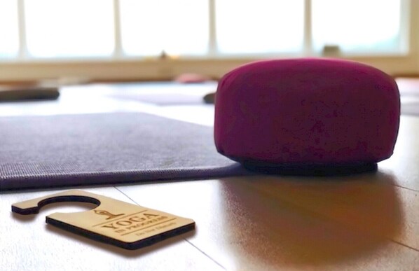 A yoga mat, a pink cushion, and a yoga block on a wooden floor. - Bei.Gretel Well Being (Struppen)