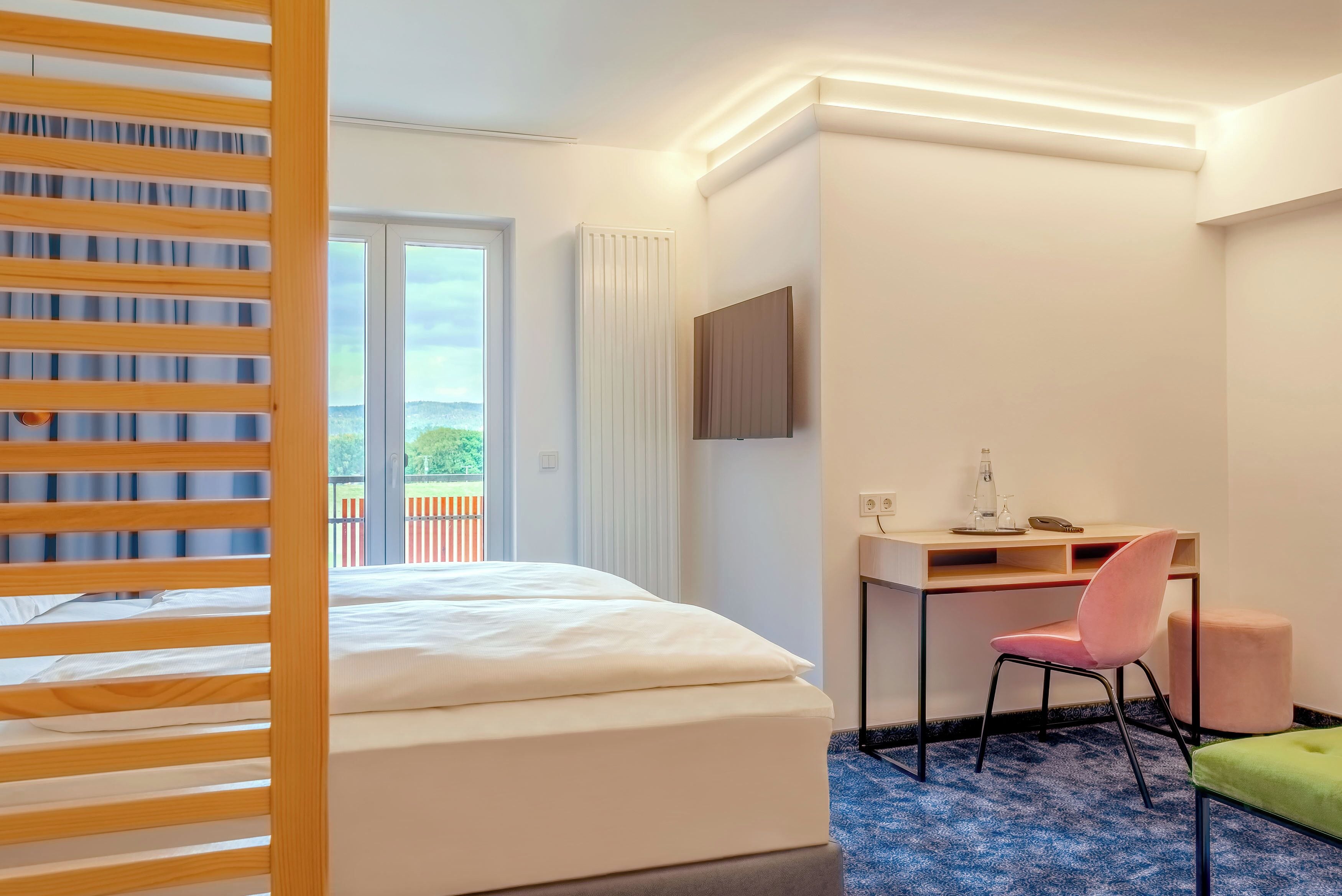 Ett hotellrum med en säng, ett skrivbord, en stol och utsikt över omgivningarna.