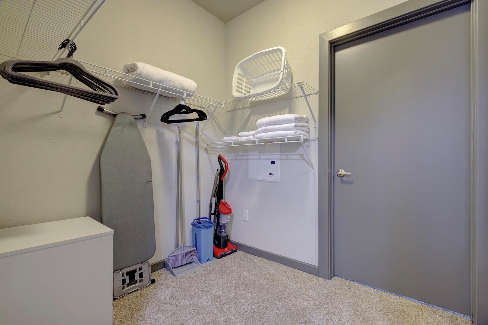 A laundry room with a washing machine, dryer, and ironing station.