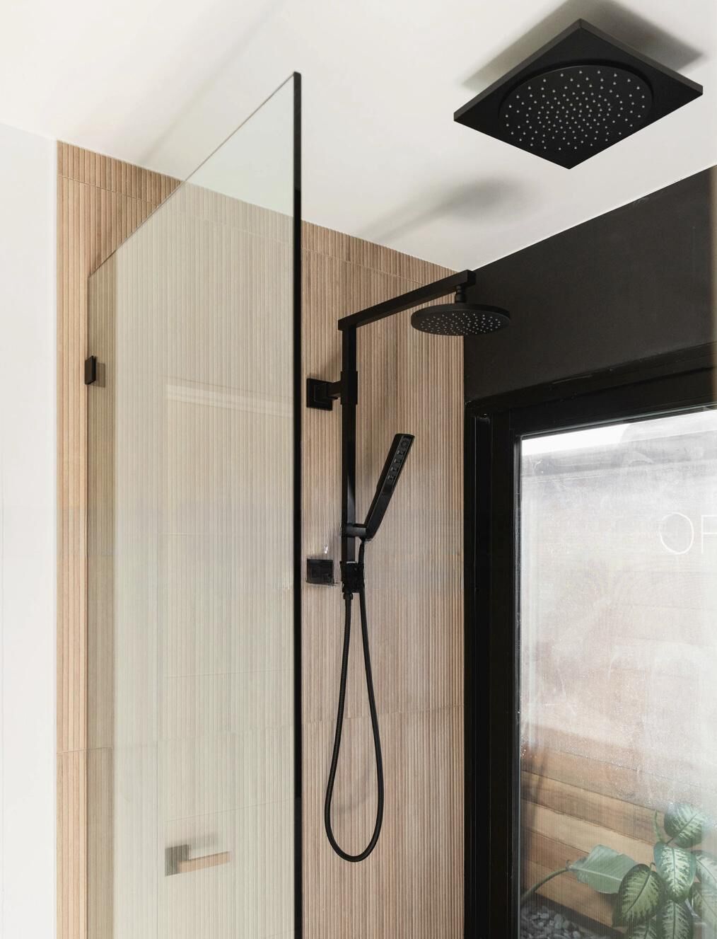 Une douche moderne dotée d’un pommeau de douche à main et d’un pommeau de douche à pluie fixe.