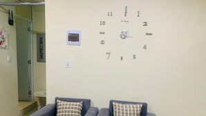 A waiting area with two armchairs, a wall clock, and a small thermostat.