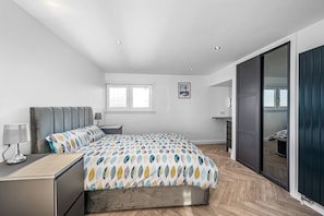 A modern bedroom with a bed, bedside table, lamp, and a large window. - Sea Views Luxury Apartment Free Parking - Coast Ap (Arbroath)
