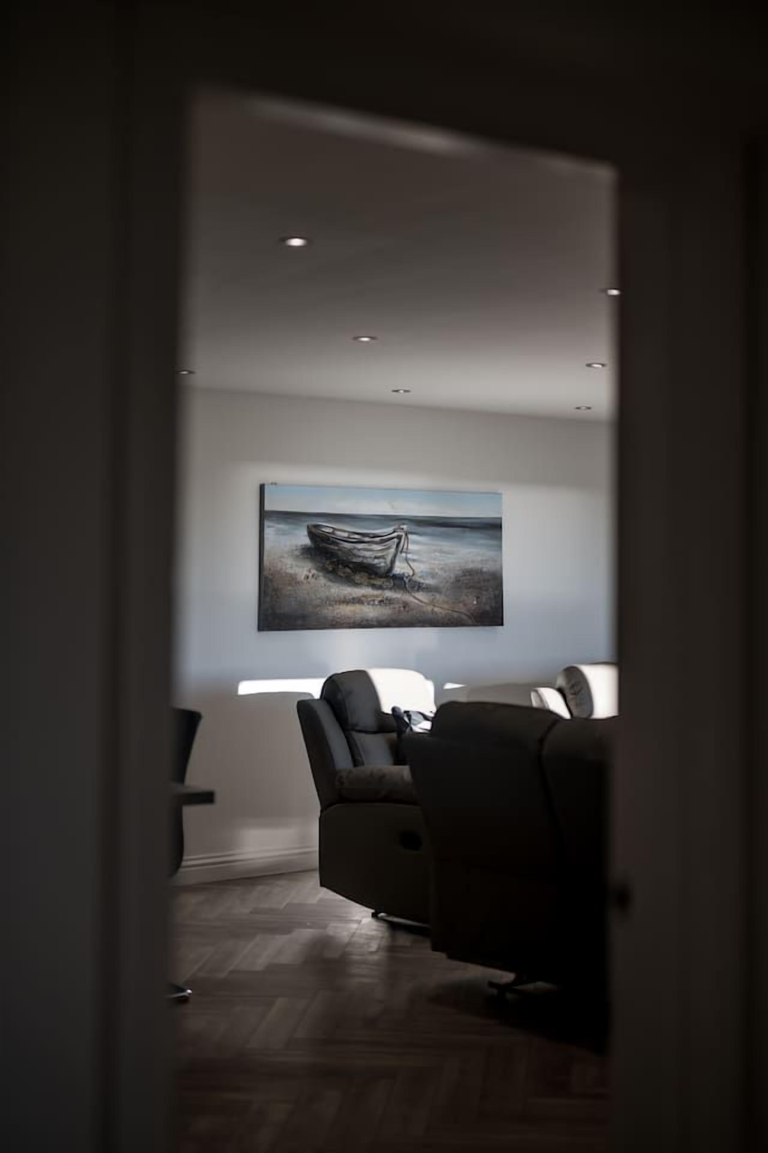 Una sala de estar moderna con un cuadro grande de un barco en el agua, un sofá y una mesita de centro.