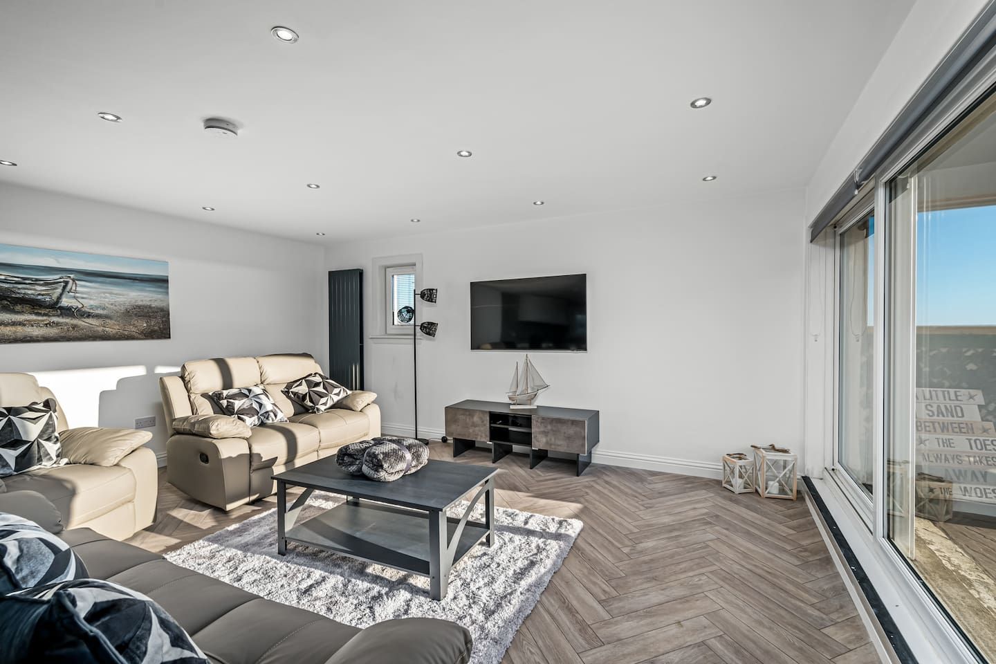 A modern living room with a sofa, coffee table, and a TV mounted on the wall.