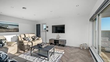 A modern living room with a sofa, coffee table, and a TV mounted on the wall.