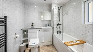 A modern bathroom with a shower, toilet, sink, and a wooden shelf. - Sea Views Luxury Apartment Free Parking - Coast Ap (Arbroath)