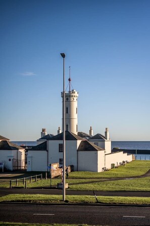 A lighthouse with a tower, a grassy area, and a clear sky. - Sea Views Luxury Apartment Free Parking - Coast Ap (Arbroath)