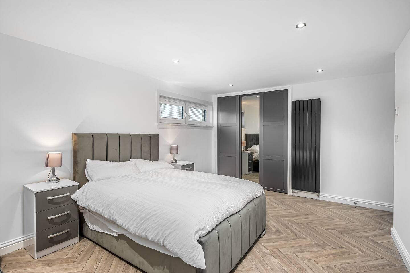 A modern bedroom with a bed, bedside tables, a wardrobe, and a walk-in closet.