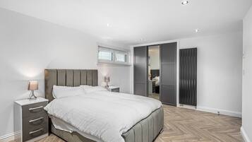 A modern bedroom with a bed, bedside tables, a wardrobe, and a walk-in closet.
