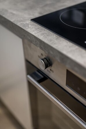 A kitchen with a stainless steel countertop and a black induction cooktop. - Sea Views Luxury Apartment Free Parking - Coast Ap (Arbroath)