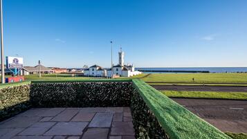 A coastal view with a restaurant sign, a white building with a tower, and a clear sky.