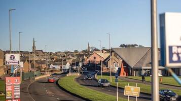 A road with multiple lanes and a roundabout. There are signs for a restaurant and a hotel.