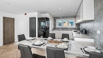 A modern kitchen with a dining area, equipped with a refrigerator, stove, and sink.