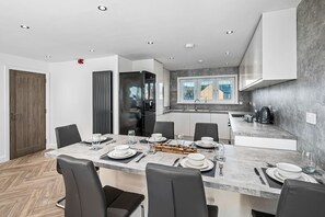 Une cuisine moderne avec un coin repas, équipée d’un réfrigérateur, d’une cuisinière et d’un évier.