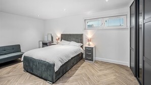 A modern bedroom with a bed, bedside tables, a desk, and a sofa. - Sea Views Luxury Apartment Free Parking - Coast Ap (Arbroath)