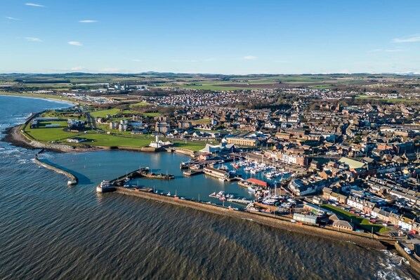 An aerial view of a coastal town with a marina, residential areas, and a prominent lighthouse. - Sea Views Luxury Apartment Free Parking - Coast Ap (Arbroath)