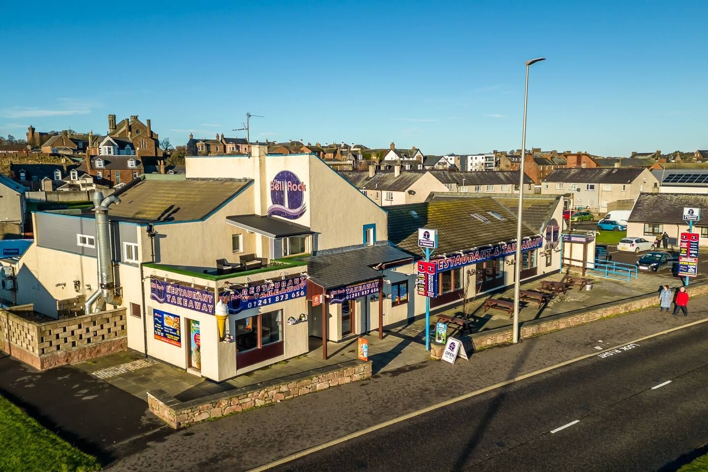 Een kustplaats met een opvallend restaurant en afhaalmaaltijdzaak genaamd 'Bell Rock'.