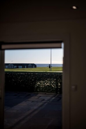 A view through a doorway to an outdoor area with a building and a body of water. - Sea Views Luxury Apartment Free Parking - Coast Ap (Arbroath)