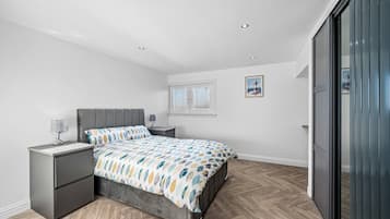 Een moderne slaapkamer met een bed, nachtkastjes, een raam en een deur.