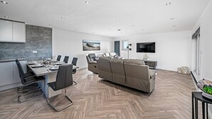A modern living space with a dining area, sofa, and television. - Sea Views Luxury Apartment Free Parking - Coast Ap (Arbroath)