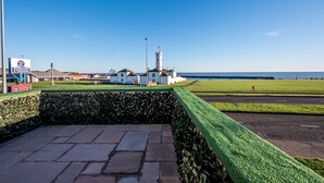 A coastal area with a lighthouse, a restaurant, and a grassy field. - Luxury Apartment with Sea Views Balcony (Arbroath)