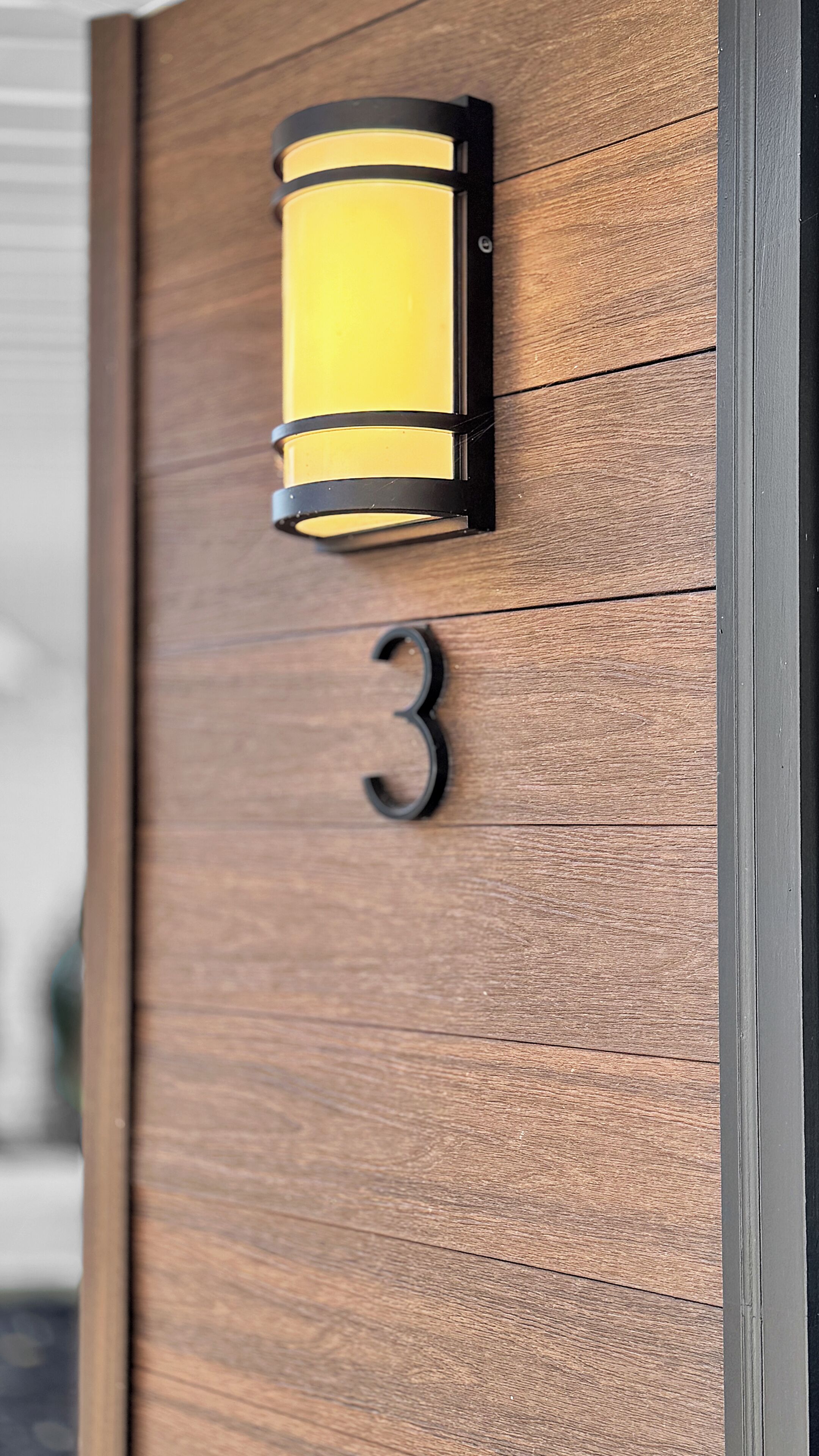 A wooden door with a number '3' and a wall-mounted light fixture.