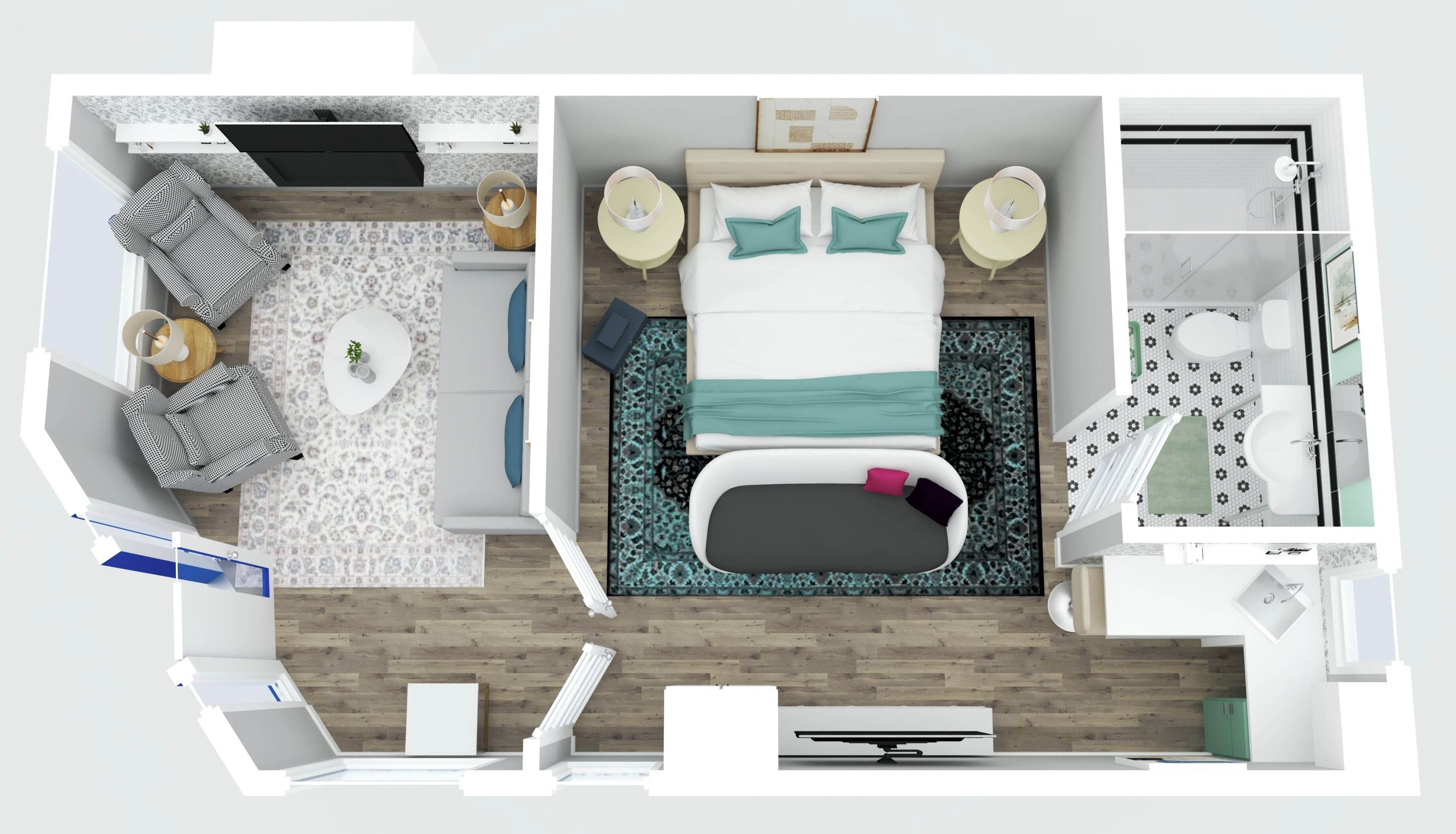 Quarto de hotel com cama, mesas de cabeceira, área de estar com sofá e poltronas, pequena mesa com abajur e banheiro com chuveiro e vaso sanitário.