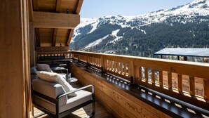 A wooden balcony with a view of snow-covered mountains.