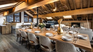 A spacious dining area with a long wooden table set for a meal, surrounded by modern chairs.