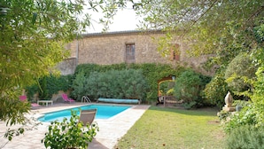 A backyard with a swimming pool, a stone building, and a grassy lawn. - Harvesters' house (Aigues-Vives)