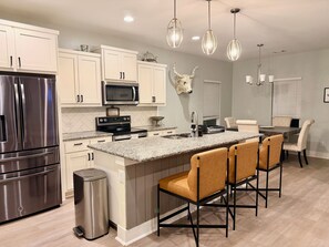 A modern kitchen with stainless steel appliances, granite countertops, and pendant lighting. - Bertram Tranquility- 3 Bedroom 2 Bath Hideaway (Bertram)