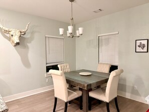 A dining room with a wooden table, four upholstered chairs, a chandelier, and a wall-mounted bull's head decoration. - Bertram Tranquility- 3 Bedroom 2 Bath Hideaway (Bertram)