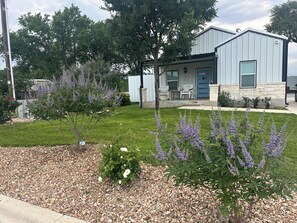 A residential property with a stone facade, a front porch with seating, and a well-maintained lawn. - Bertram Tranquility- 3 Bedroom 2 Bath Hideaway (Bertram)
