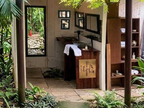 Un piccolo bagno rustico con un lavabo in pietra, mensole in legno e una segnaletica che indica che si trova in un albergo.