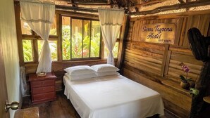 Une pièce en bois avec un lit, une table de chevet, une fenêtre avec des rideaux et une enseigne indiquant « Sierra Tayrona Hostel ».