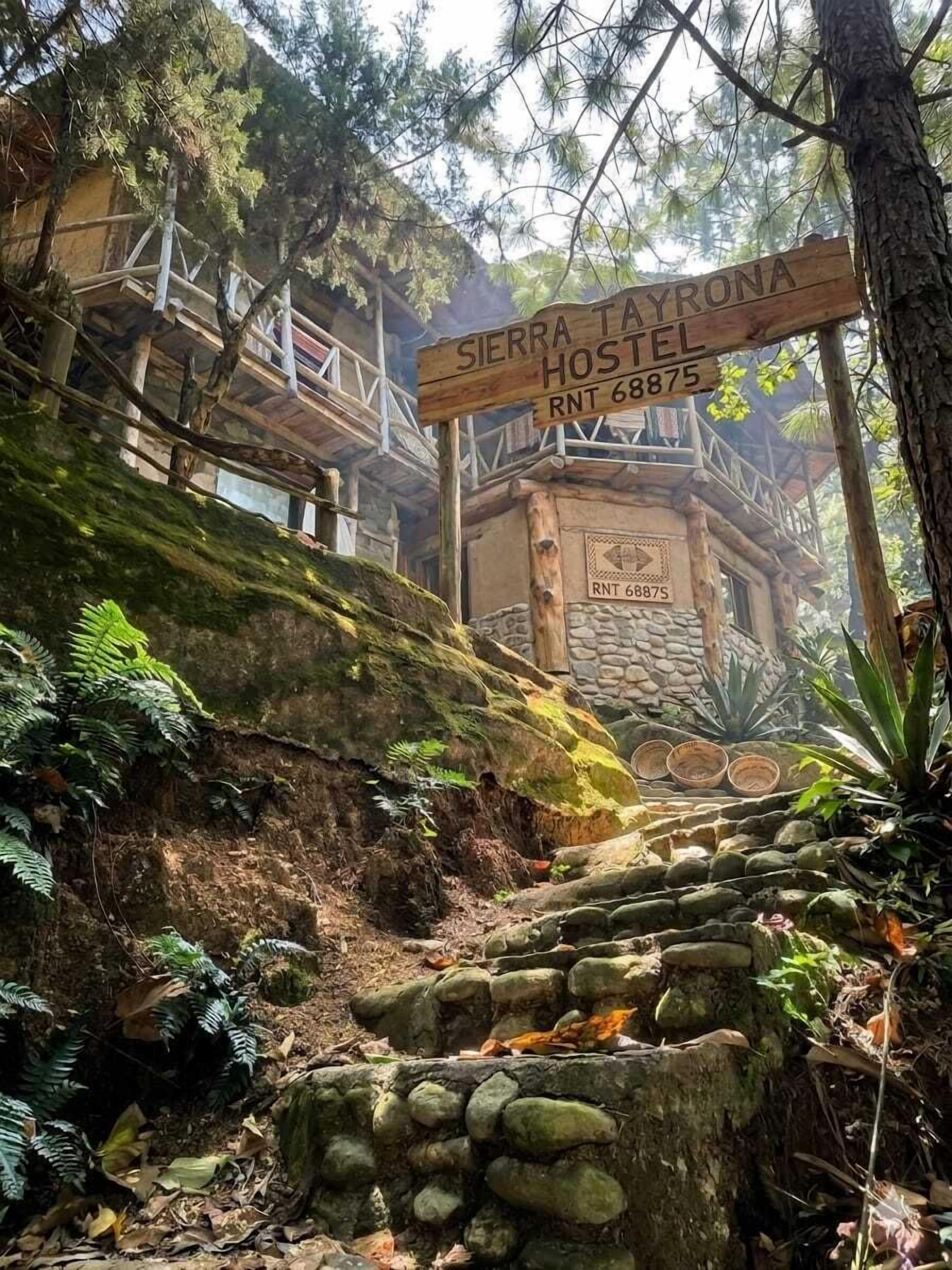 A wooden sign for Sierra Hostel with a rustic stone building in the background.