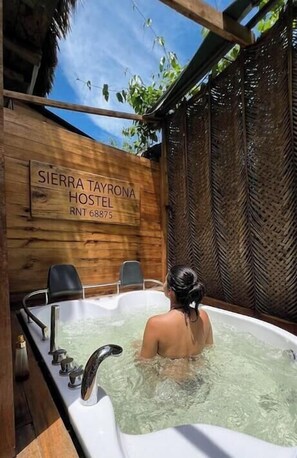 Una vasca idromassaggio con un cartello di legno che riporta la scritta 'SIERRA TAYRONA HOSTEL RNT 68875' sullo sfondo.