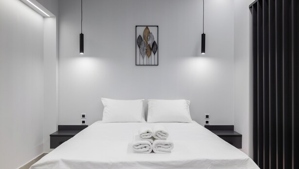 A modern hotel room with a neatly made bed, two bedside tables, and a wall-mounted artwork. - Kamara Urban Retreat by #db Premium Stay Apartments  (Thessaloniki)