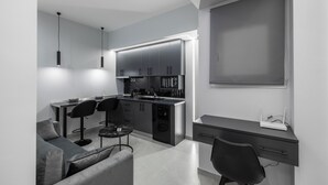 A modern kitchen with a dining area, a sofa, and a desk with a computer. - Kamara Urban Retreat by #db Premium Stay Apartments  (Thessaloniki)