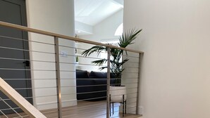 Een modern interieur met een trap, een vlakke nok en uitzicht op een zithoek.
