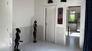 Un couloir avec une porte blanche, une petite statue et un tableau accroché au mur.