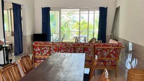 Un espace repas avec une longue table en bois, des chaises en osier et un luminaire suspendu.