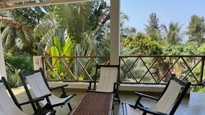 Un espace extérieur abrité, aménagé avec des meubles en osier et offrant une vue sur la végétation tropicale.