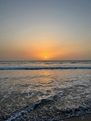 A beach at sunset with waves gently lapping the shore.