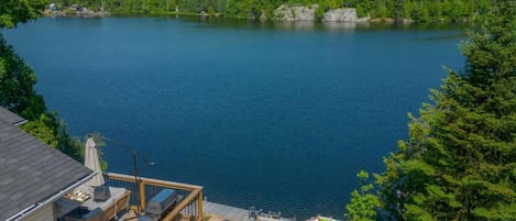 A lakeside property with a deck, outdoor seating, and a view of the lake.
